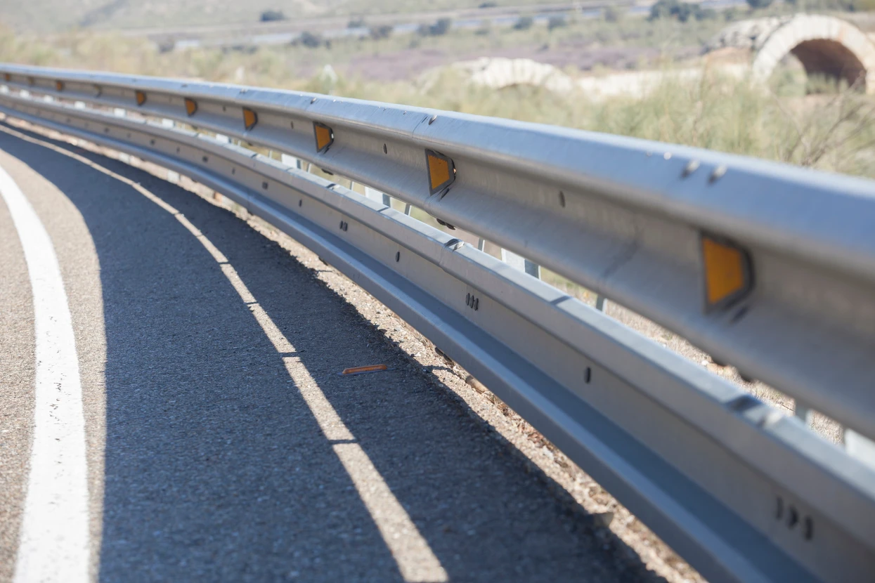 Scène extérieure d'une route asphaltée avec glissière de sécurité métallique galvanisée le long du bord