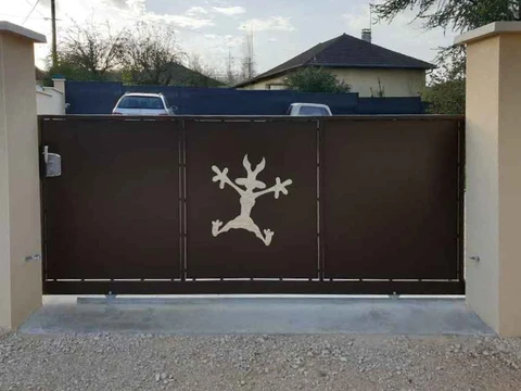 Portail coulissant motorisé en acier laqué marron foncé, découpe laser figurative représentant un personnage animé style cartoon (coyote) en position de saut