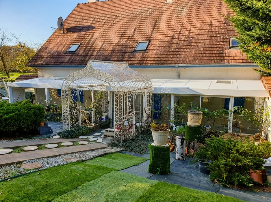 Terrasse extérieure avec pergola adossée à une maison pavillonnaire